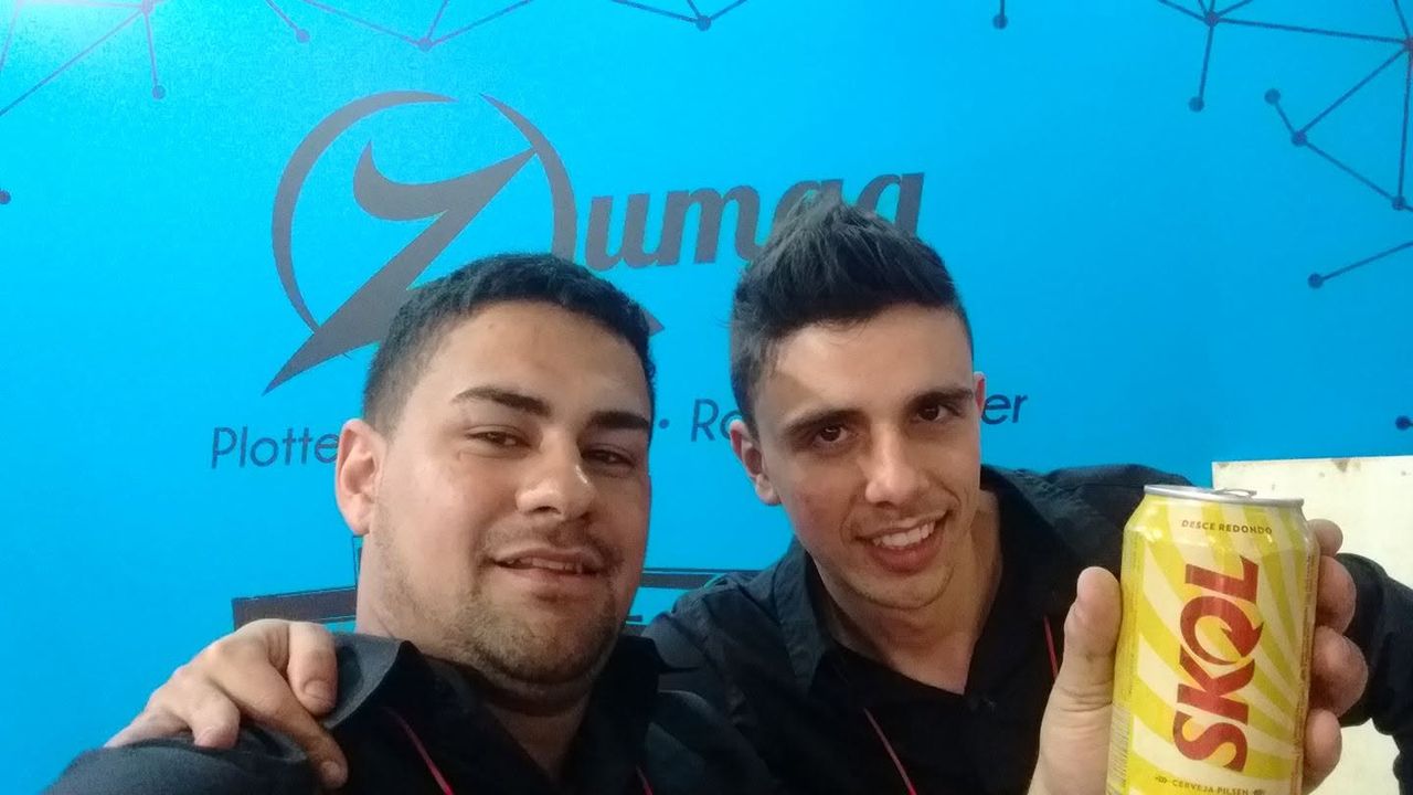 Os dois fundadores da Tibatron lado a lado, em foto de 2015, quando ainda trabalhavam com máquinas antes de abrir a empresa.